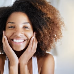 Smiling woman with curly hair. These are the 12 best natural hair products of 2021. Shop the products that will promote healthier hair growth, shine, and movement for your natural hair.
