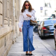 Woman walking down the street wearing flare jeans and a white shirt