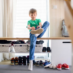 Image of a little boy putting on shoes in his mudroom