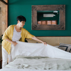 Senior Asian woman doing her morning routine, making up her bed at home