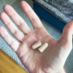 Hand holding earplugs and earplugs in a jar