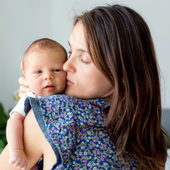 Young mother, kissing and hugging her newborn baby boy, tender, care, love, positive emotions