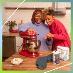 Two women in kitchen with red kitchen aid and hands on a white kitchen aid