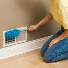 Woman kneeling cleaning a vent cover