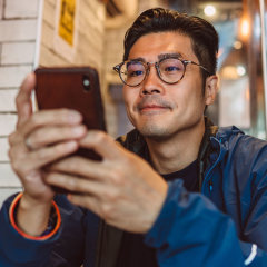 Young handsome Asian man making order from the digital menu on smartphone in restaurant.