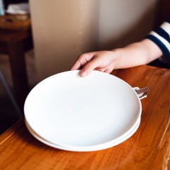 A woman distributing empty plates on a wooden table