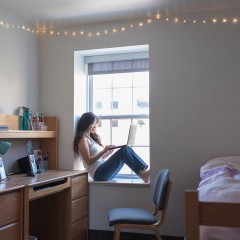 Young woman college student in her dorm room with laptop