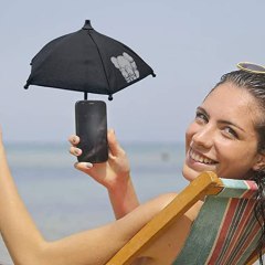 Woman at the beach, using her phone with a tiny umbrella over it