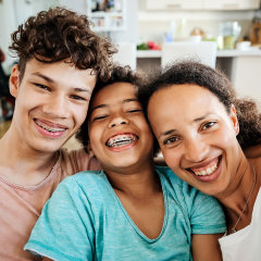 A portrait of a mom sitting on the couch with her two sons at home.