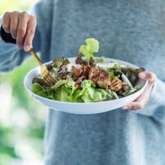 a woman holding and eating chicken salad
