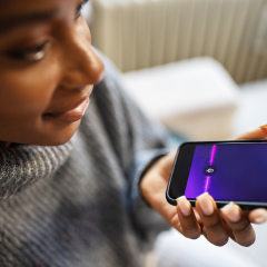 Close-up of young woman talk with virtual digital voice recognition assistant. African female using voice assistant on smartphone.