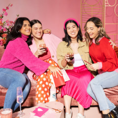 four women embracing while exchanging Galentine's day gifts.