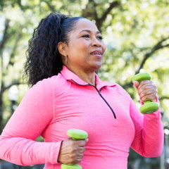 African-American woman powerwalking with hand weights.