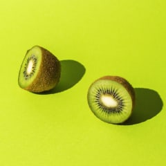 Sliced fruit of fresh kiwi on a bright green background.