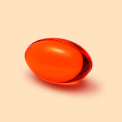 Red transparent CoQ10 supplement capsule isolated on yellow background