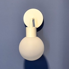 Poplight base adhered to blue wall with person holding Poplight with shade.