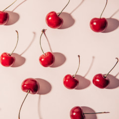Cherries and hard shadows. Flat lay of cherries on a on a beige background.