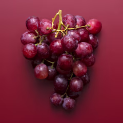 Red grapes on a matte dark red background.