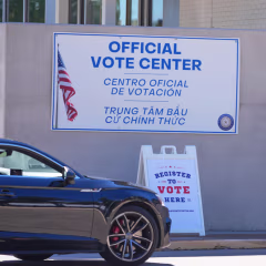 Voluntarios les indican a los conductores dónde registrarse para votar en un punto de atención frente al Departamento de Elecciones del Condado de Dallas, en Dallas, el 5 de octubre de 2026. 