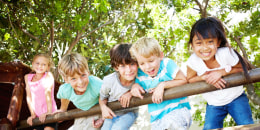 Group of five kids hanging on a fence