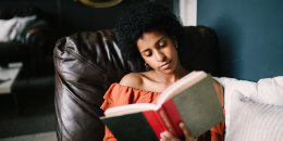 Woman sitting on her couch reading a book