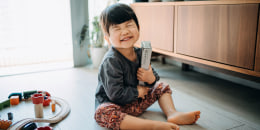 Cute little Asian girl receiving a gift from her parents, hugging the gift and smiling joyfully in the living room at home