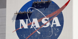 Workers on scaffolding repaint the NASA logo at the Kennedy Space Center in Cape Canaveral, Fla., on May 20, 2020.