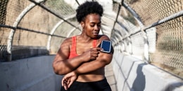 Healthy woman using phone on armband before exercising