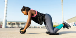 young sportive woman training with an ab wheel