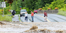 Onlookers check out a flooded road on July 10, 2023 in Chester, Vermont. Torrential rain and flooding has affected millions of people from Vermont south to North Carolina.