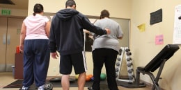 Dos adolescentes con sobrepeso hacen ejercicio con la ayuda de un instructor en un gimnasio de Reedley, California.
