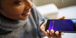 Close-up of young woman talk with virtual digital voice recognition assistant. African female using voice assistant on smartphone.