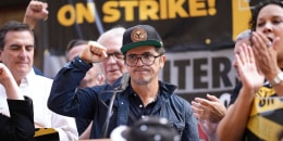 El actor y productor John Leguizamo, usando una gorra, levanta el puño derecho durante una jornada de acción de los sindicatos SAG (actoral) y WGA (guionistas) el 14 de septiembre de 2023 en Nueva York