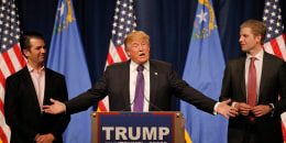 Then-Republican presidential candidate Donald Trump gestures to his sons Donald Trump Jr., left, and Eric Trump as he addresses supporters at his caucus night rally in Las Vegas in 2016. 