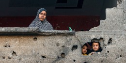 A Palestinian woman and children look out from a damaged building Rafah, southern Gaza, on Dec. 15, 2023.