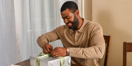 a man opening a gift wrapped in silver paper
