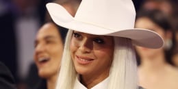 Beyoncé, wearing a cowboy hat, smiles at the Grammy Awards