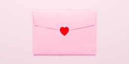 Envelope Sealed With Red Colored Heart Sticker on Pink Colored Background.