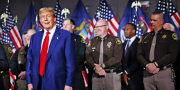 Former President Donald Trump is surrounded by members of law enforcement as he speaks at a campaign event on April 2, 2024 in Grand Rapids, Mich.