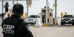 Customs and Border Protection agents direct vehicles.