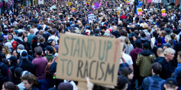 Anti-racism counter protesters gathered with a sign that reads "STAND UP TO RACISM".