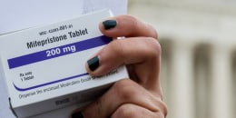 abortion-rights activist holds a box of mifepristone pills outside the Supreme Court
