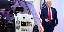Donald Trump walks between police cars