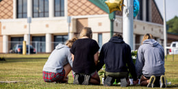 Students kneel in front of a makeshift memorial.