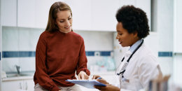 Happy woman going through her medical data with black female doctor at the clinic.