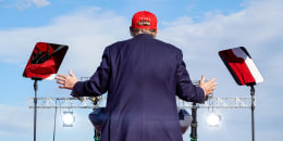 Donald Trump, back to camera, speaks at a podium outside