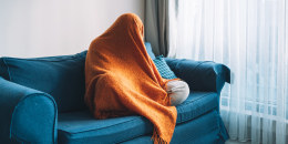 Person on the couch with blanket over head.