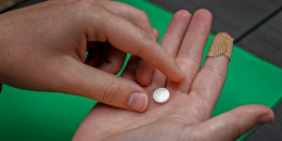 A hand holds a Mifepristone pill.