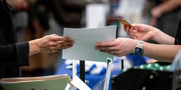 An attendee hands a resume to a recruiter at a job fair hiring event in Sacramento, Calif., on Feb. 27, 2025. 