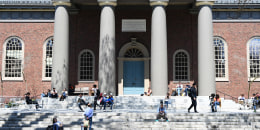 People sitting on the steps of a campus building at Hardvard